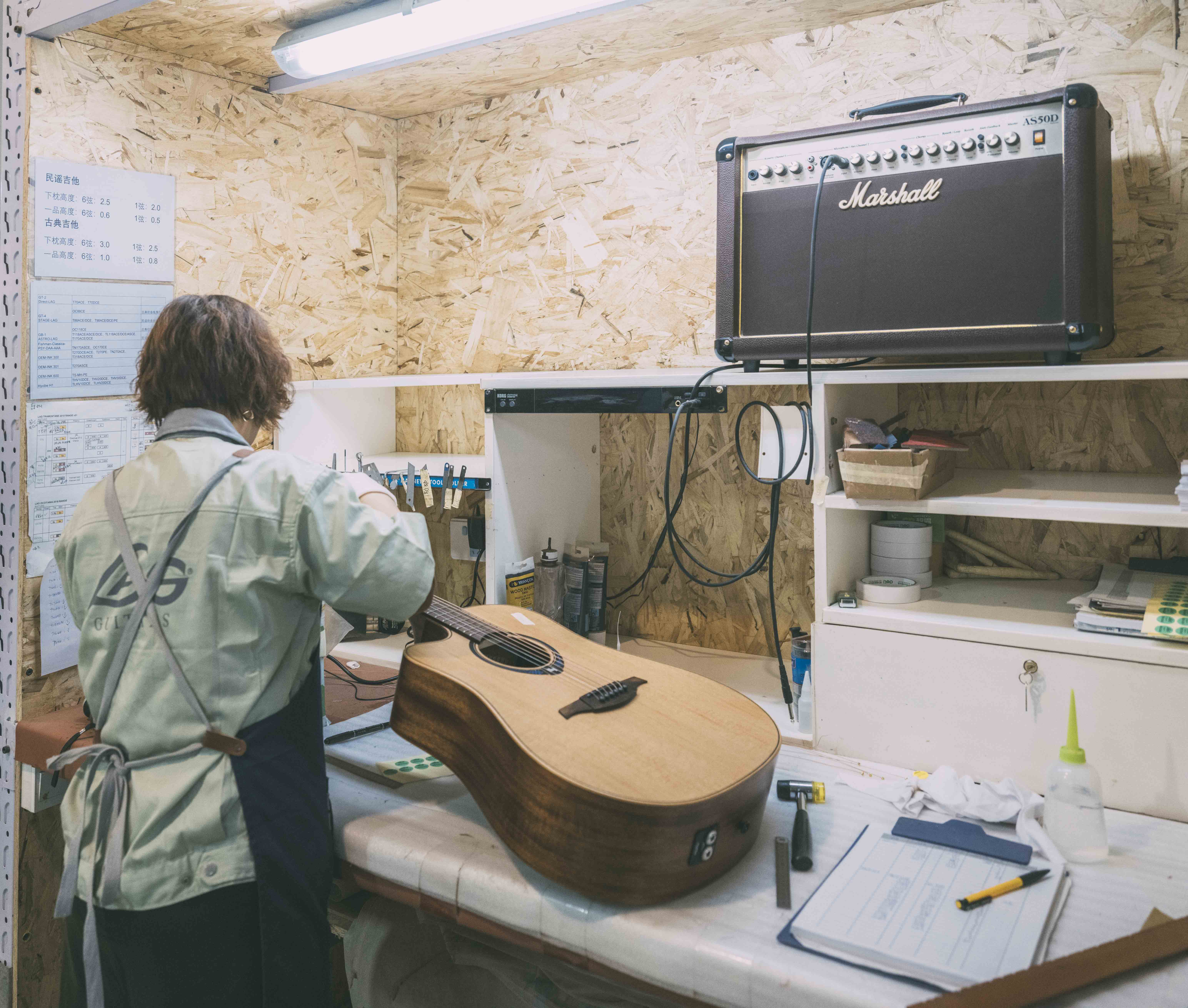 Une femme contrôle la qulaité d'une guitare Lâg THV30DCE dans l'usine Lâg à Tianjin pour compléter le processus de fabrication avant expédition de cette dernière